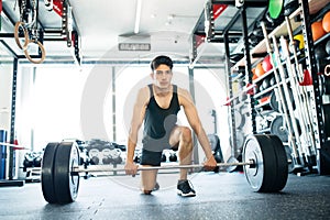 Young fit hispanic man in gym lifting heavy barbell