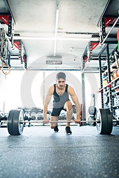 Young fit hispanic man in gym lifting heavy barbell