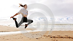 Young fit lady jumping high on beach ocean, active european woman working out outdoors, panorama with copy space