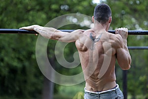 Young fit man doing exercises on the horizontal bar