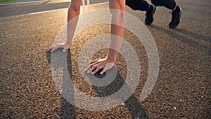 Young fit man doing push ups in the morning outdoor on road in sunset with strong sun flare