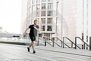 Young fit man doing urban running workout on asphalt road sprinting in sport and healthy lifestyle concept. Big city on