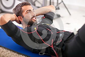 Young fit man exercise on electro muscular stimulation machine