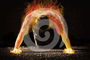 Young fit man in fire showing his muscles toned and stylized