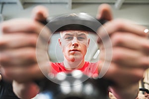 Young fit man in gym lifting kettlebell. Close-up.