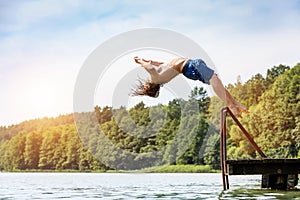 Young fit man jumping into a lake.