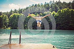 Young fit man making a jump into a lake.