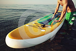 Young fit man on paddle board floating on lake.