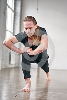 Young fit man stretching legs doing forward lunge.