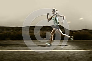 Young fit sport woman running outdoors on asphalt road in mountain landscape and dramatic light set for advertising