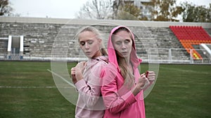 Young fit sporty caucasian pretty twin sisters boxing outdoors at stadium field