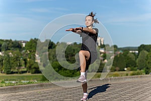 Young, fit and sporty girl in black clothes stretching after the workout in the urban city park