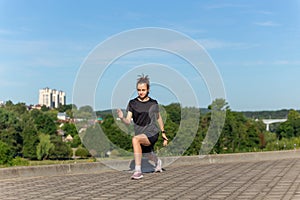 Young, fit and sporty girl in black clothes stretching after the workout in the urban city park