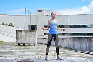 Young, fit and sporty woman jumping with a skipping rope. Fitness, sport, urban jogging and healthy lifestyle concept.