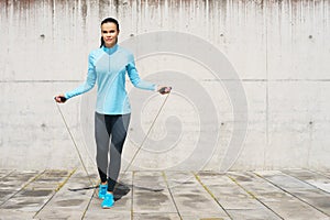 Young, fit and sporty woman jumping with a skipping rope. Fitness, sport, urban jogging and healthy lifestyle concept.