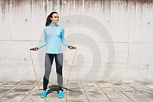 Young, fit and sporty woman jumping with a skipping rope. Fitness, sport, urban jogging and healthy lifestyle concept.