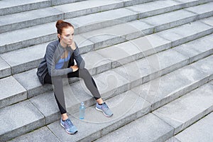 Young, fit and sporty woman resting after the training. Fitness, sport, urban jogging and healthy lifestyle concept.