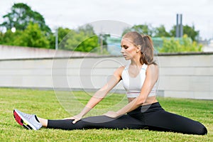 Young, fit and sporty woman stretching in the park. Fitness, sport, urban and healthy lifestyle concept.