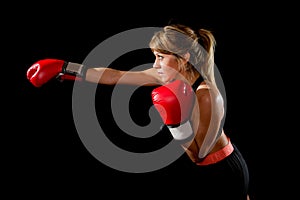 Young fit and strong attractive boxer girl with red boxing gloves fighting throwing aggressive punch training workout in gym