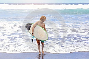 young fit surfer man with surfboard runs into ocean or sea with big waves for surfing. Concept of extreme sport, fitness