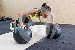 Young fit woman doing push up on medicine ball at gym.