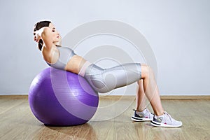 Young fit woman exercising in a gym. Sports girl is training cross fitness with Pilates Balls