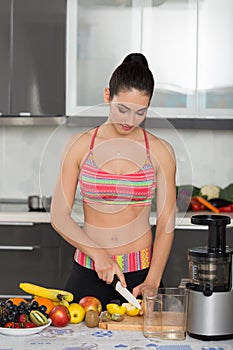 Young fit woman with fruits, in the kitchen