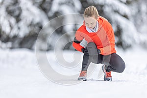 A young fit woman holds a reinforced knee after straining her cruciate ligament during cross-country training in the snow during