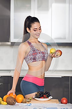 Young fit woman in the kitchen holding fruits