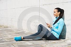 Young and fit woman listening to the music outdoor.