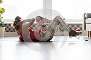 Young fit woman lying on mat doing bicycle crunch exercise