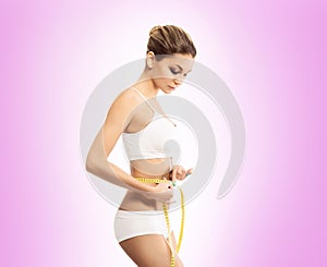 Young and fit woman measuring her waist with a tape