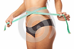 Young fit woman measuring her waistline