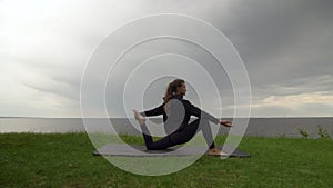 Young fit woman practice yoga on coast near the lake or sea. Woman doing One Legged King Pigeon - Mermaid Pose