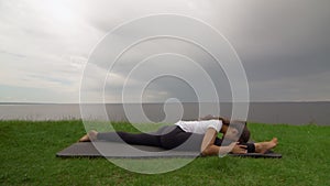 Young fit woman practice yoga on coast near the lake or sea. Woman sitting in Front Splits Hanumanasana pose
