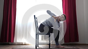 Young fit woman practicing yoga exercise called Twisted Chair Pose or Parivrtta Utkatasana