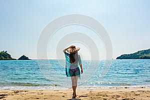 Young fit woman standing on a tropical beach in the summer vacation