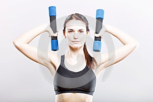 Young fit woman training with dumbbells