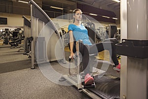 Young fit woman use abductor machine in a fitness center. Portrait of fitness girl in the gym, lifestyle concept..