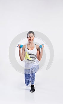 Young fit woman working out with dumbells. Studio shot.
