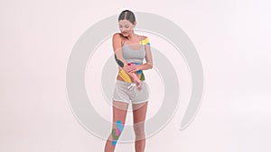 Young fit women showing on her body applied elastic kinetic tape. Kinesiology physical therapy.