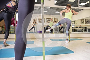 Young fit Women on a Yoga Pilates group class in gym. They stretch, stay in asana poses in sport outfit. Daylight. Indoors