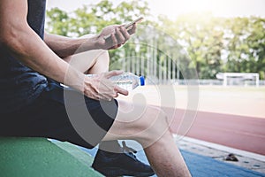 Young fitness athlete man resting on bench with bottle of water preparing to running on road track, exercise workout wellness