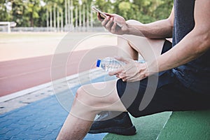 Young fitness athlete man resting on bench with bottle of water preparing to running on road track, exercise workout wellness