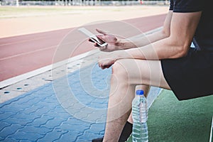 Young fitness athlete man resting on bench with bottle of water preparing to running on road track, exercise workout wellness