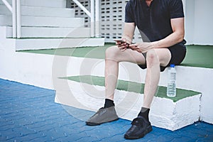 Young fitness athlete man resting on bench with bottle of water preparing to running on road track, exercise workout wellness