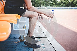 Young fitness athlete man resting on bench with bottle of water preparing to running on road track, exercise workout wellness