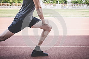 Young fitness athlete man running on road track, exercise workout wellness and runner stretching legs before run concept