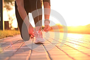 Young fitness attractive sporty girl runner ties up the shoelaces on her sports shoes getting ready to run.