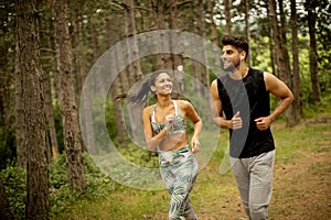 Young fitness couple running at the forest trail